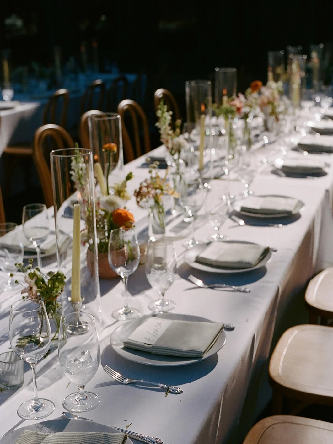 Bud vases, tapers and place settings down the length of a long white table at 27 Vines