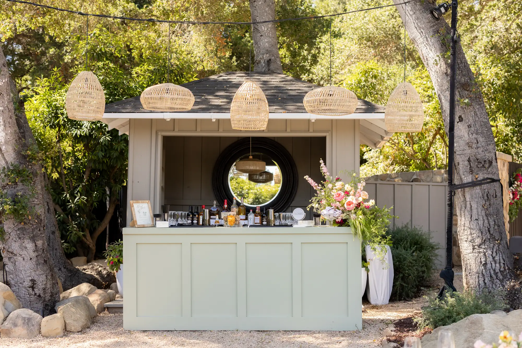 A styled All Purpose Flower outdoor bar under rattan pendant lights