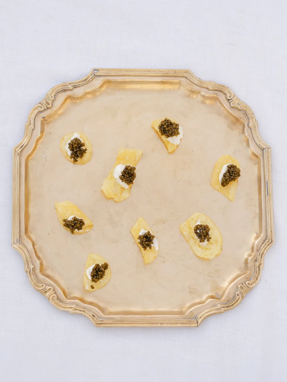 Delicate caviar-topped canapés on a gold tray