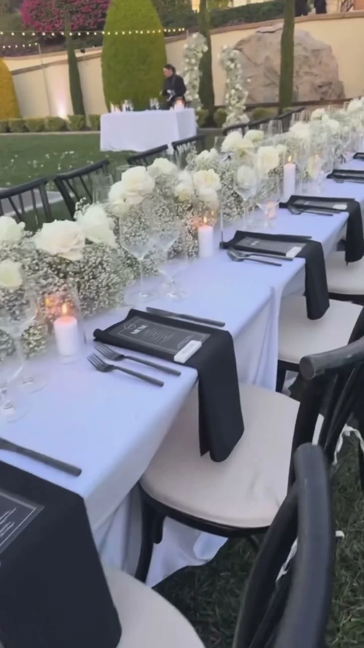 A long table lined with white roses, black napkins, and candles at Chateau Noland