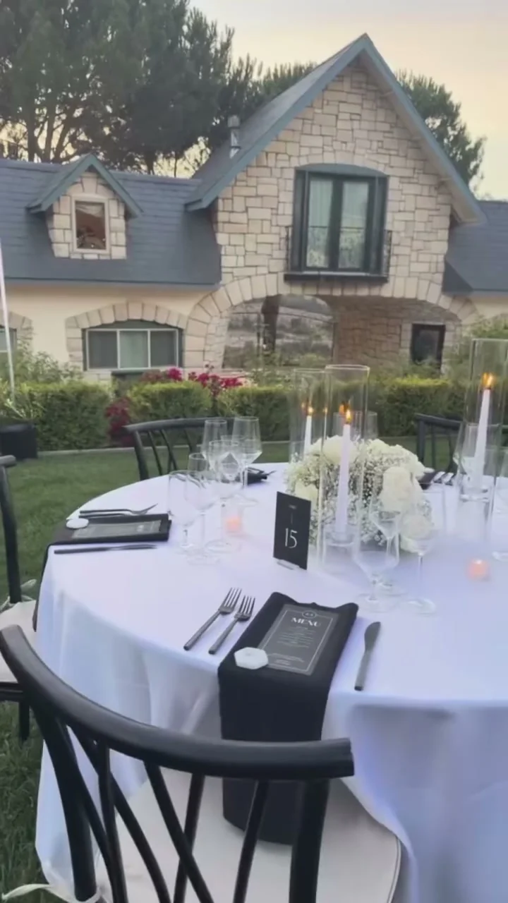 A round table set with menu cards, taper candles, and white florals at Chateau Noland