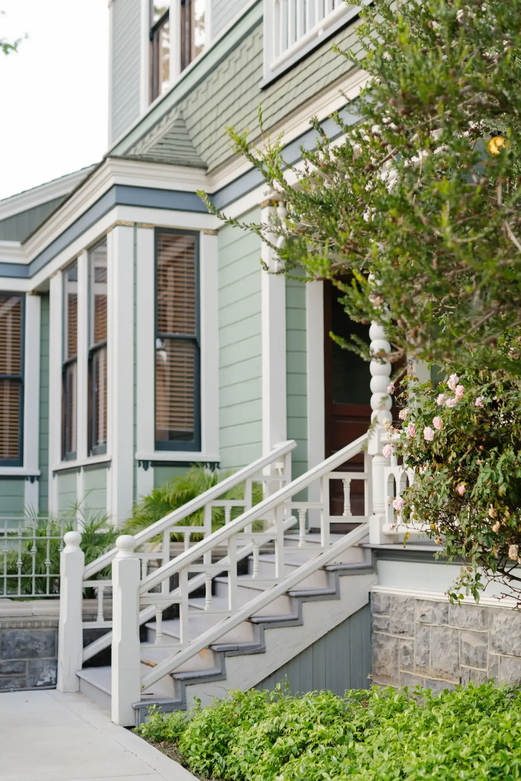 The white porch steps of a Victorian at Heritage Square, roses climbing the corner beside them