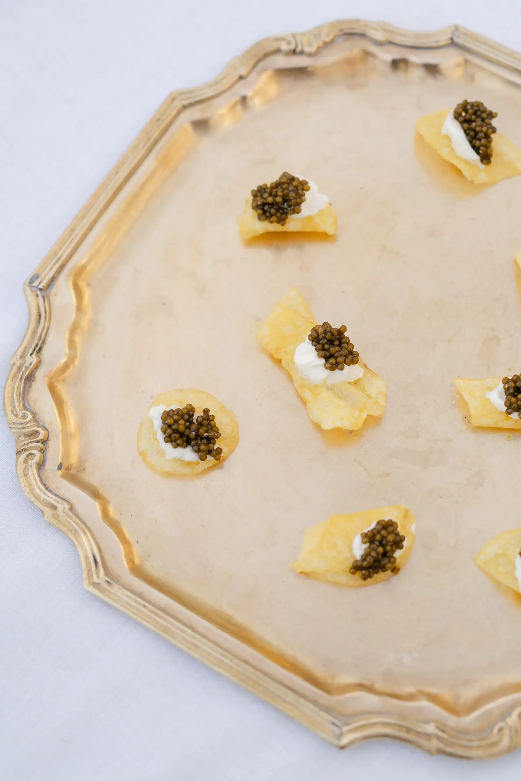 Caviar and crème fraîche on truffle chips, spaced across a scalloped gold tray, from the gala we catered at Heritage Square