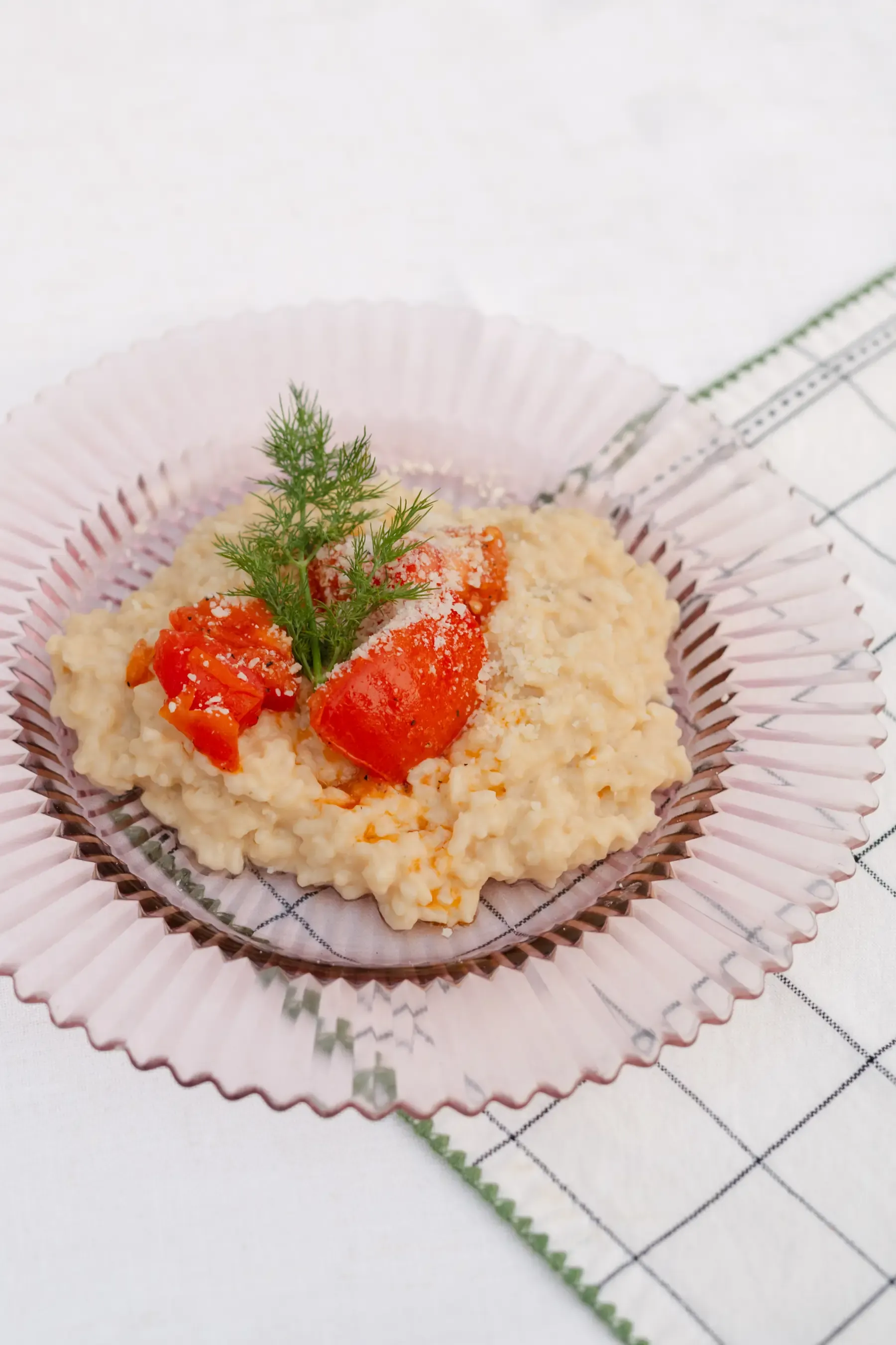 Creole risotto with stewed heirloom tomatoes and dill, plated on pink pressed glass at Heritage Square