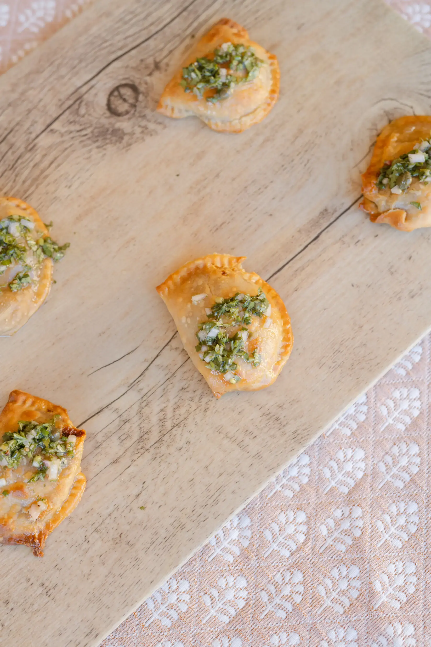 Beef empanadas topped with chimichurri on a wooden board