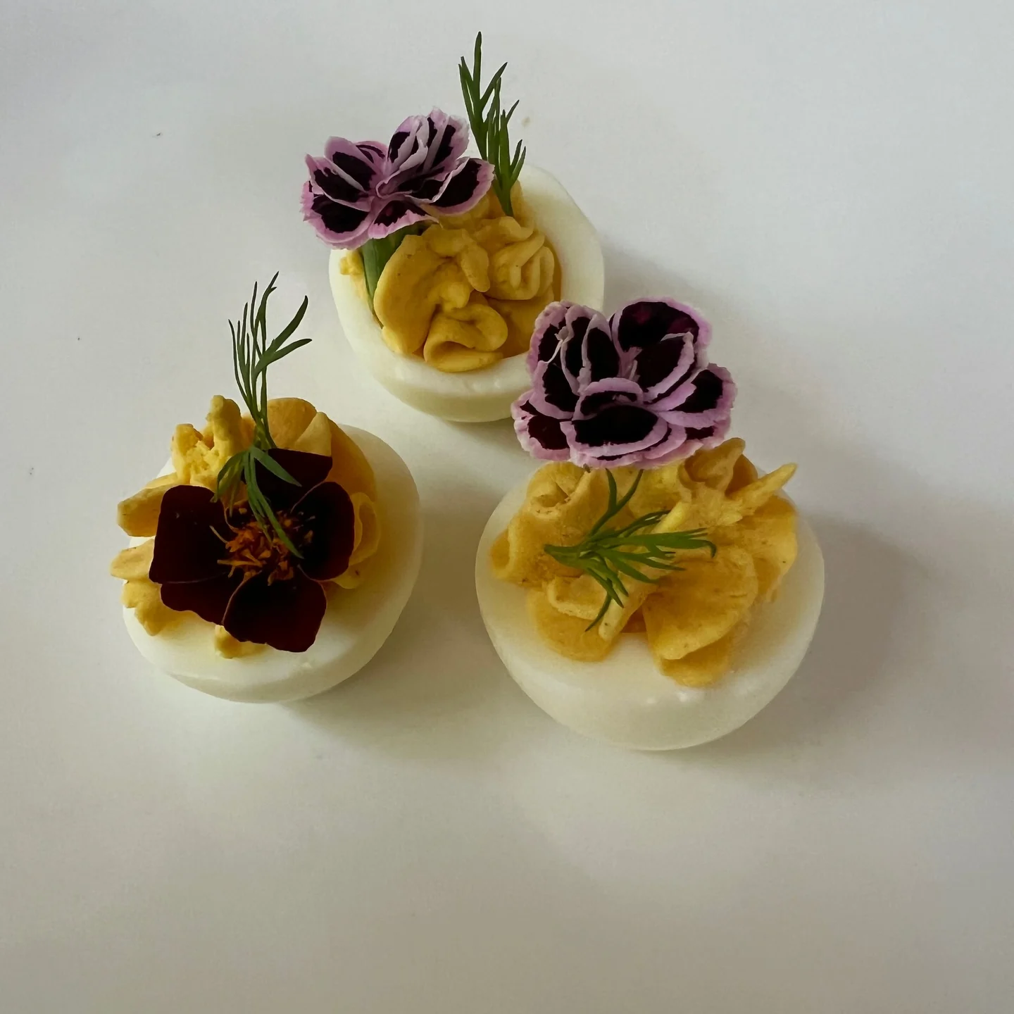 Deviled eggs piped and topped with whole edible flowers and dill