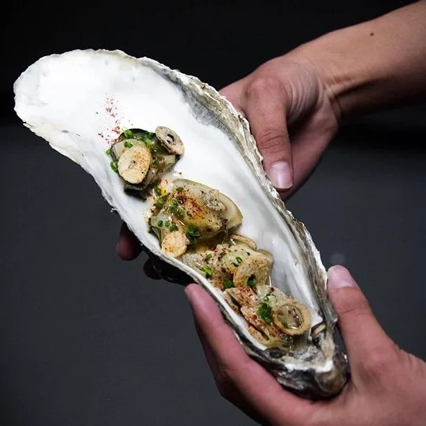 A canapé served in an oyster shell, finished with chives and chilli
