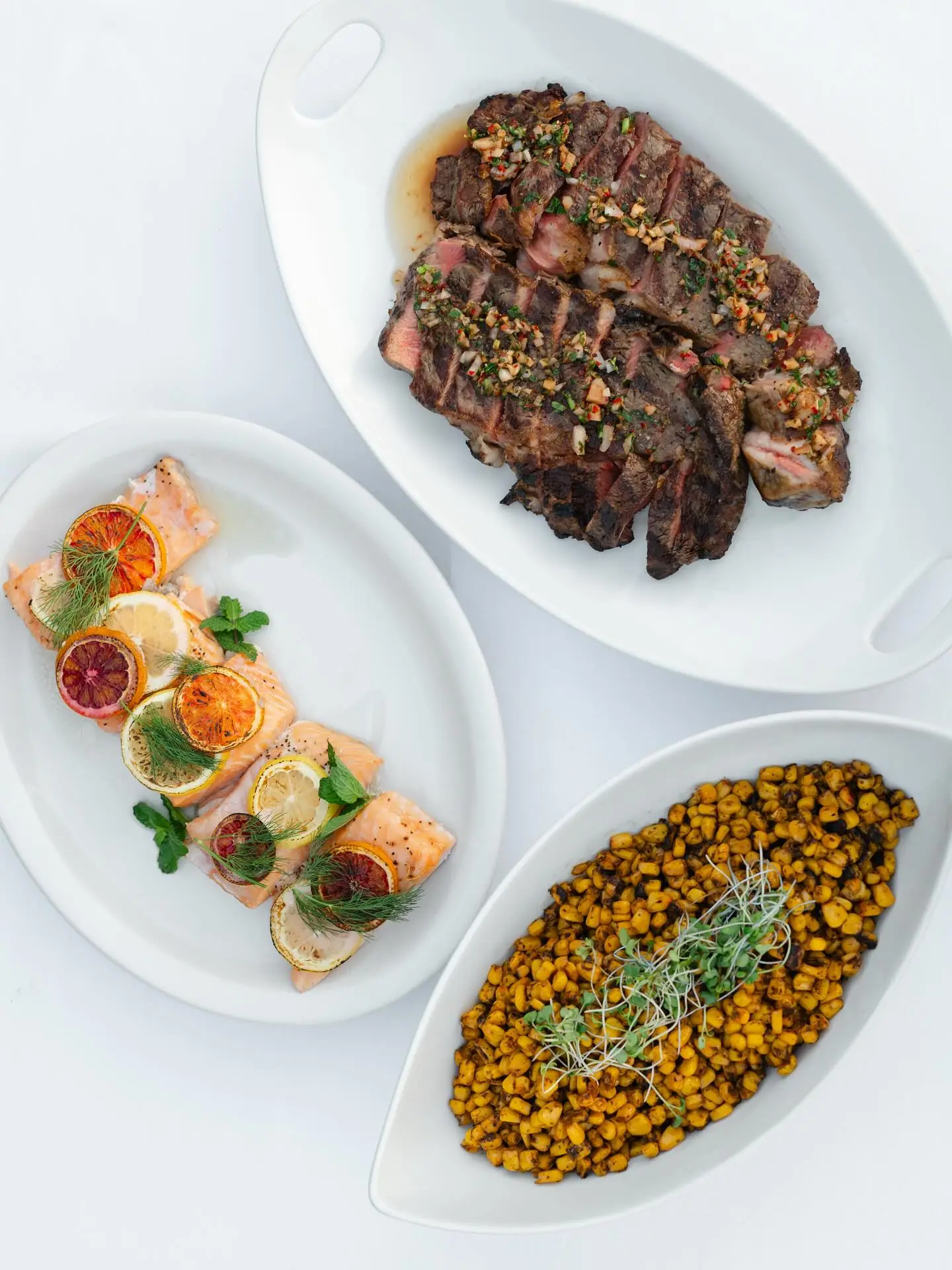 Platters of grilled rib-eye, citrus salmon, and charred corn salad from a Rancho Carmina wedding menu