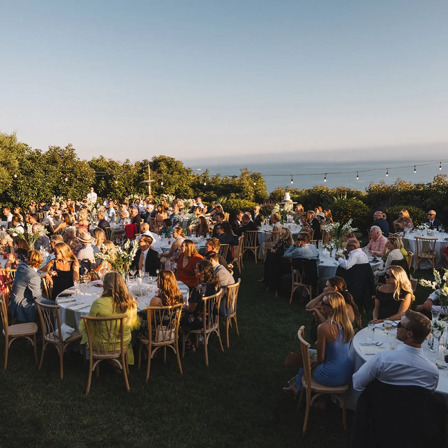 Guests dining above the ocean at sunset at Regina Ranch