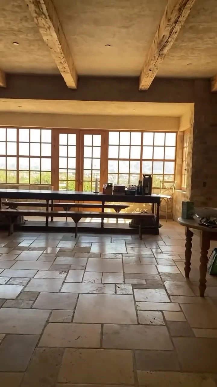 A long wooden table and benches under beamed ceilings in the stone-floored hall at Sunstone Villa