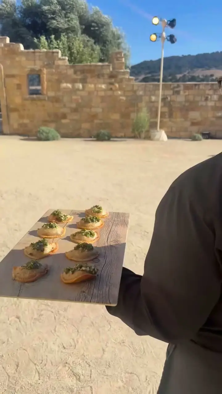 A server carrying a board of empanadas with chimichurri past the limestone wall at Sunstone Villa