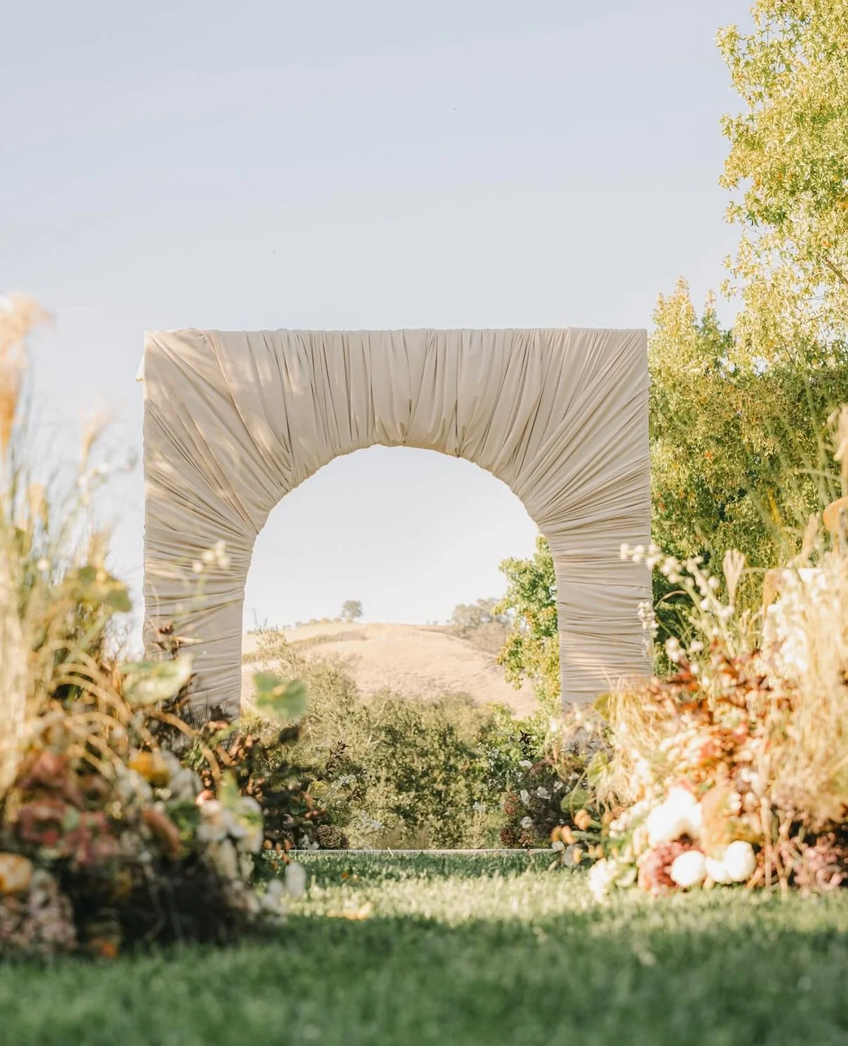 A draped fabric arch and florals on the lawn with the hills beyond at Santa Ynez Ranch