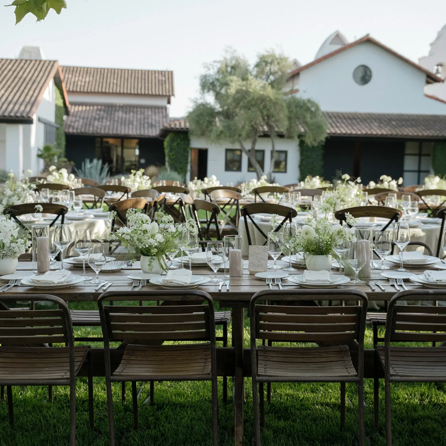 Long tables set with white florals and glassware on the lawn at Santa Ynez Ranch